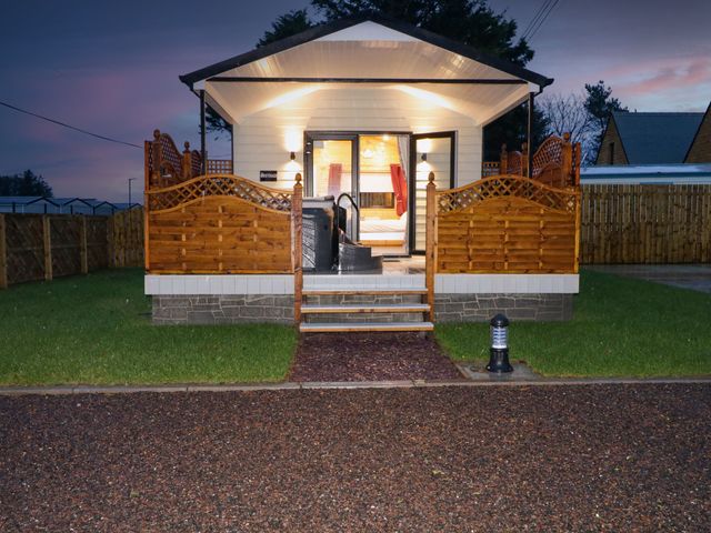 A cabin with wooden railing and steps leading to a front porch with open doors at Binevanagh Cabin in Magilligan near Castlerock