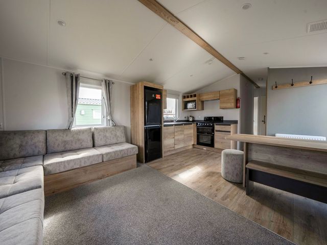 A living room with kitchen appliances and seating area at Sand and Splash - Hayling Island