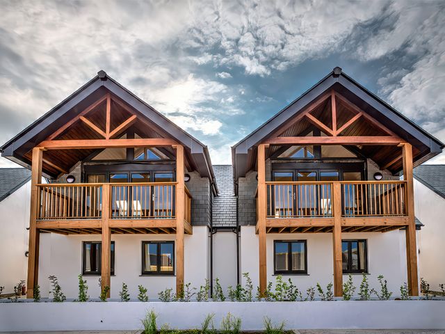 Two houses with wooden balconies and pitched roofs with sky in the background at Villa 2 Mullion