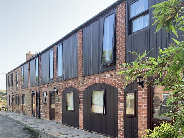 An exterior view of a brick building with multiple windows and doorways at Millers Cottage Seaville near Wigton