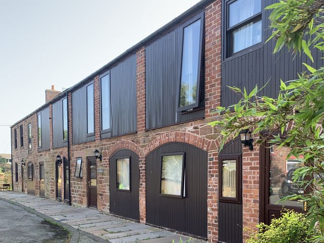 An exterior view of a building with multiple windows and doors at The Hayloft near Wigton