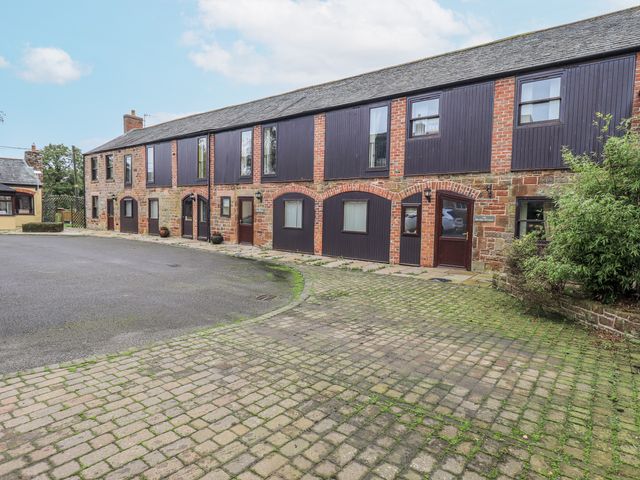 A building with windows and doors in a courtyard at The Hayloft near Wigton