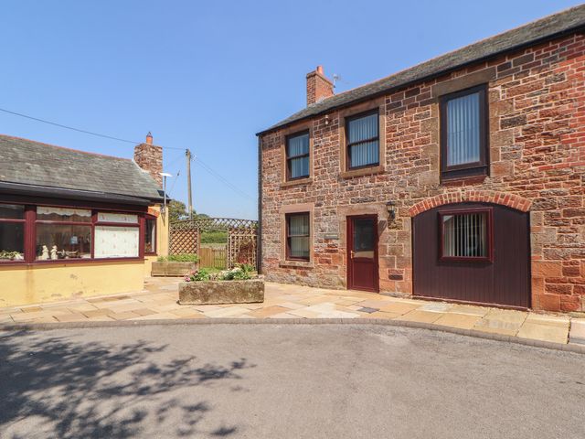 An exterior view of a brick building with windows and a door at The Coach House near Wigton