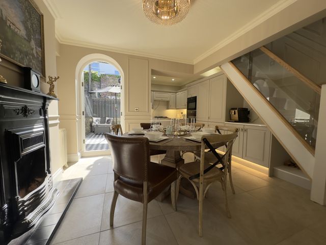 A kitchen and dining area with a round wooden table set for four and an open door to a patio at Ivy House in Conwy