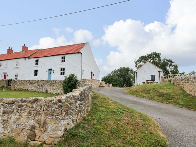 A house and road with a stone wall at Peace Cottage in Langton near Gainford