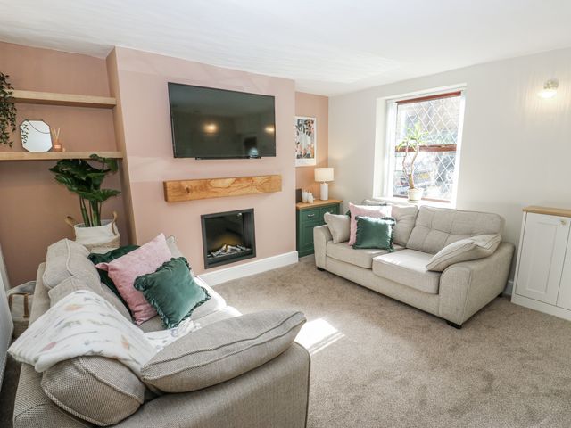 A living room with a television and fireplace at Court Street Cottage, Uppermill