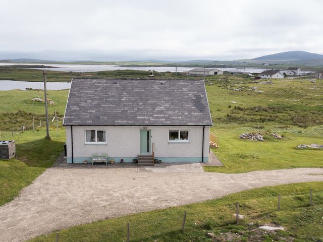 A house with a gravel path and natural surroundings at Taigh Eva near Lochmaddy