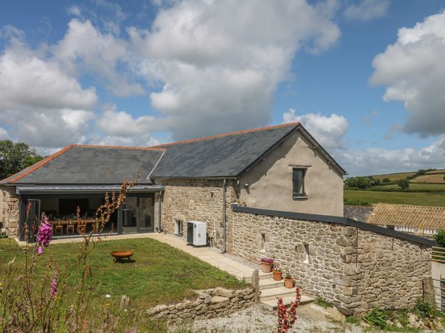 An outdoor view of a stone building with a patio and garden at Reddaway Threshing Barn near Okehampton