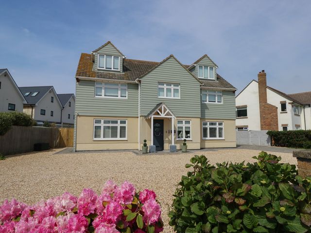 A house with a gravel driveway and flower plants at 50 Sea Road Milford On Sea