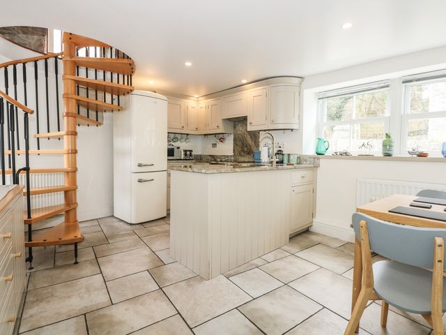 A kitchen with a spiral staircase refrigerator kitchen island and dining table at Pen-Y-Bont in Trefor