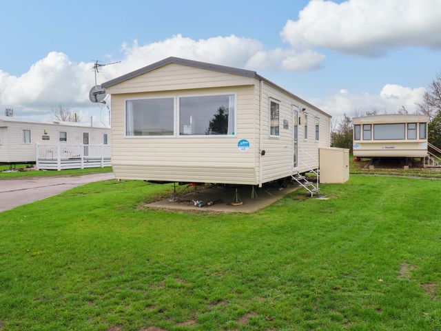 A mobile home with steps and grass area at Meadowside