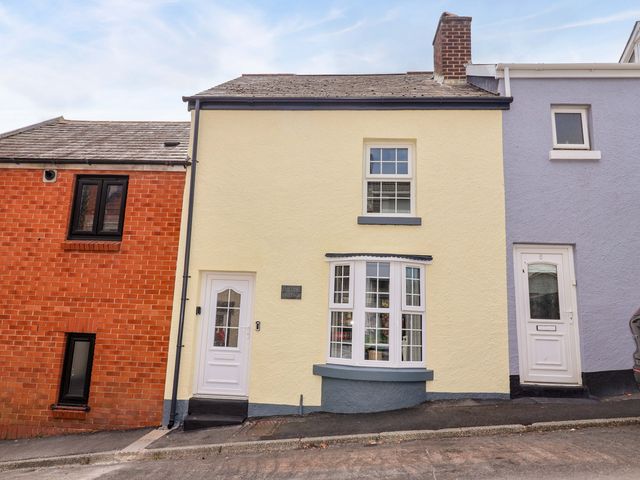 A house with a yellow facade and white windows at Lilly's Cottage in Dawlish