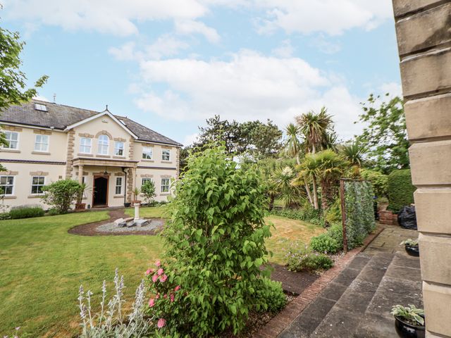 A garden with a house and pathway at Mount House Bryniau near Dyserth