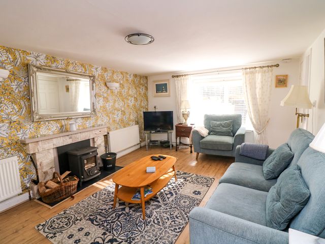 A living room with a wood-burning stove a blue sofa and armchair a wooden coffee table and a patterned rug at The Dairy in Clonsharragh near Duncannon County Wexford