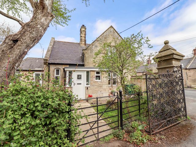 A house with a gate and tree at The Lodge in Powburn