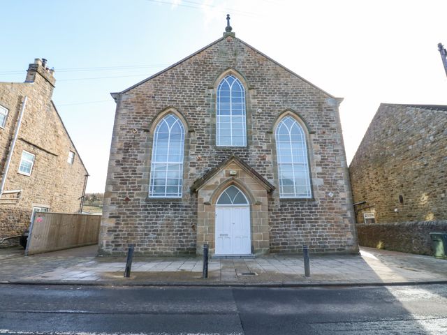A stone building with three arched windows and a white door at Aurelian House in St John's Chapel