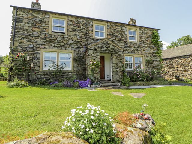 A stone house with garden and flowers at High Wood Foot in Bampton, Cumbria