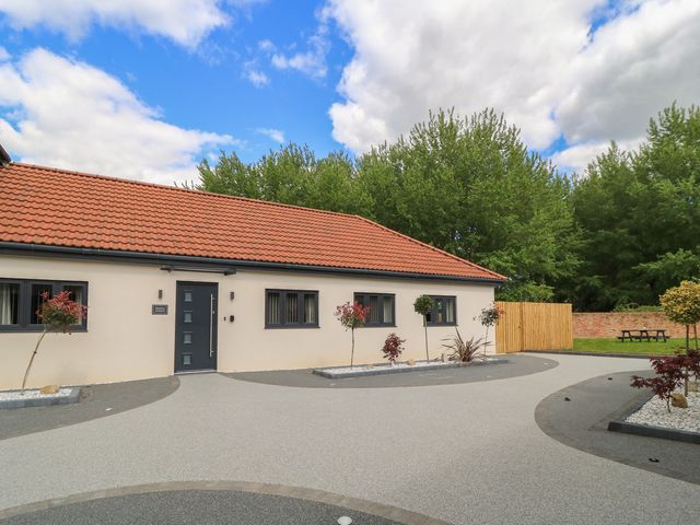 An outdoor view of a house with a pathway and seating area at Maple Lodge in Westonzoyland near Bridgwater