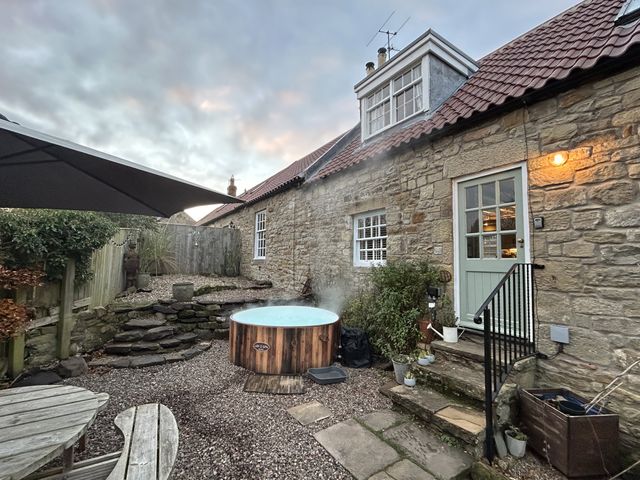 An outdoor area with a hot tub and garden features at The Poachers Pocket in Whittingham near Alnwick