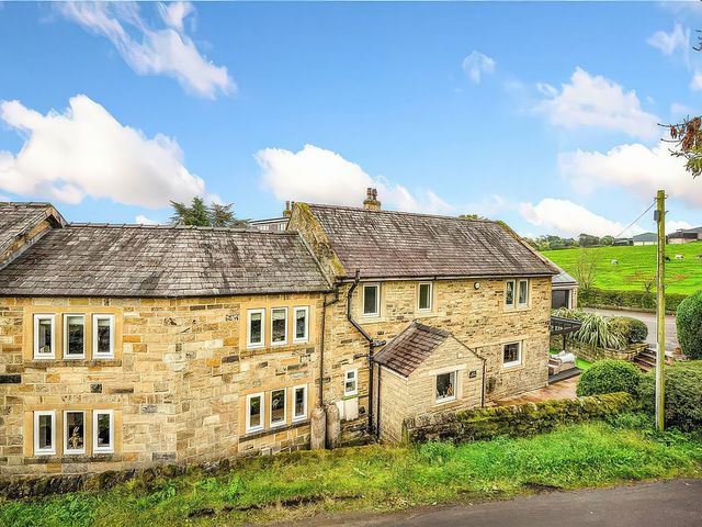 An exterior view of a stone house with a garden at Johns Cottage in Harrogate