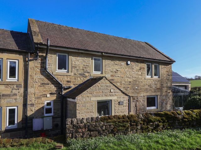 A house exterior view with multiple windows and stone walls at Johns Cottage in Hampsthwaite