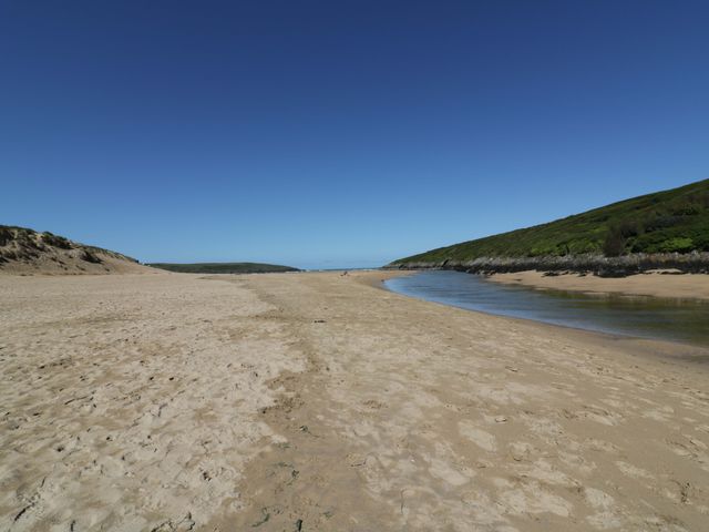 A beach with sand and a small stream at Vosporth Villa in Newquay