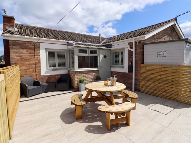 An outdoor patio with a wooden table and chairs at North Sands in Beadnell