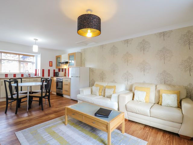 A living room and kitchen with two white sofas and a dining table with black chairs at Garden Cottage in Surlingham near Poringland