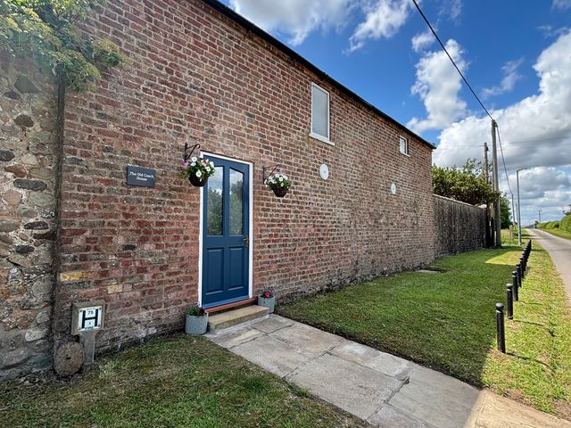 An entrance with a blue door and planters at The Old Coach House at The Vicarage Mappleton near Hornsea