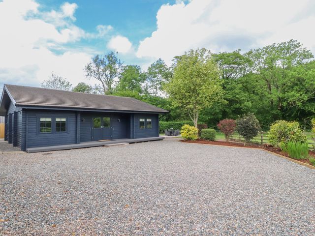 A house with a gravel area and trees at Manor Lodge in Clitheroe
