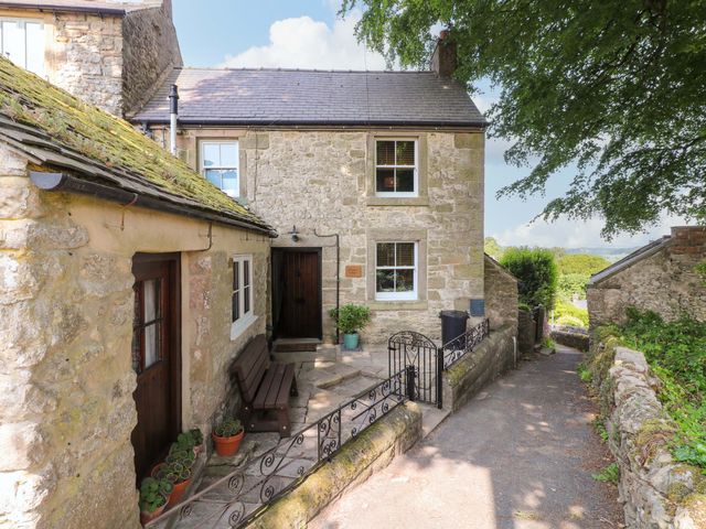 An exterior view of a stone cottage with a pathway at Chimney Cottage in Winster