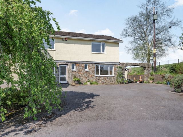 A two story house with stone and cream exterior walls a large driveway and various plants at Pant Y Cwtsh in Kidwelly