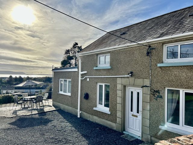 An outdoor area with a house and seating at Graig Goch in Burry Port