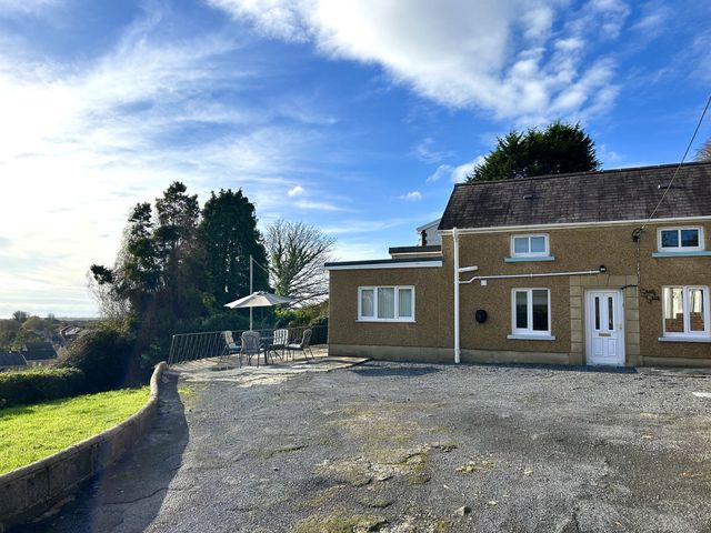 A house with a patio and umbrella at Graig Goch in Burry Port