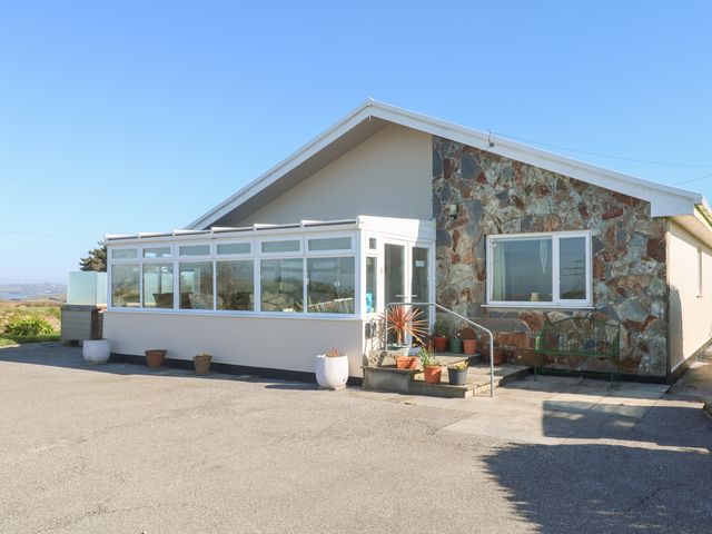 A single-story house with a stone wall and a white conservatory at Tataramoa in Rame Cross near Falmouth