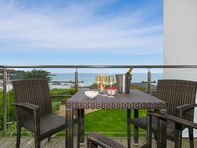 A balcony with a table and chairs overlooking the sea at Far Cliffs in St. Ives