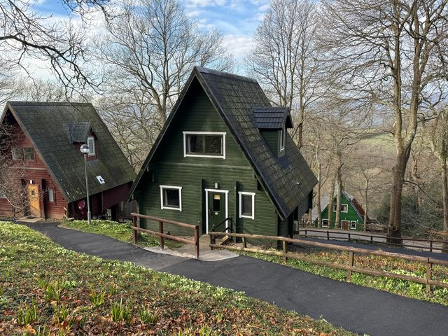 Exterior view of green and red houses along a pathway at Tor View near Finlakes Holiday Park near Chudleigh