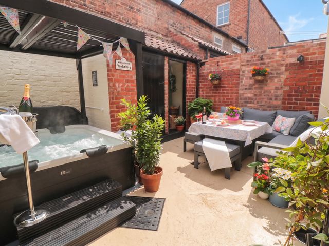 An outdoor area with a hot tub, table, and seating at 5 South Side