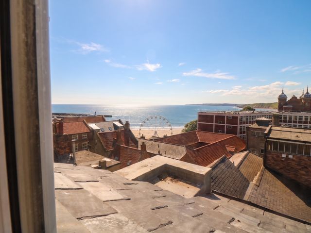 A view of the sea and buildings with a ferris wheel at The Newborough Apartment 5 Scarborough