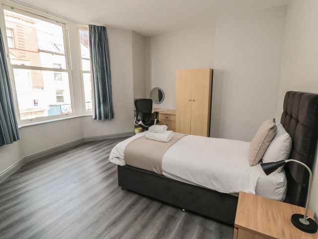 A bedroom with a bed, desk, and wardrobe at The Newborough Apartment 2 in Scarborough