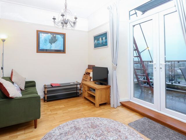 A living room with a television and balcony doors at Captain’s Quarters in Porthmadog