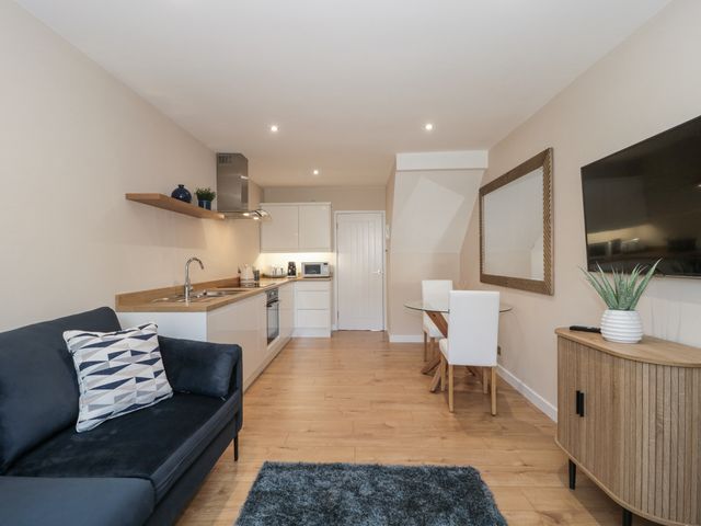 A living room with a sofa, table, and kitchen area at Royal Terrace Sunset in Weymouth