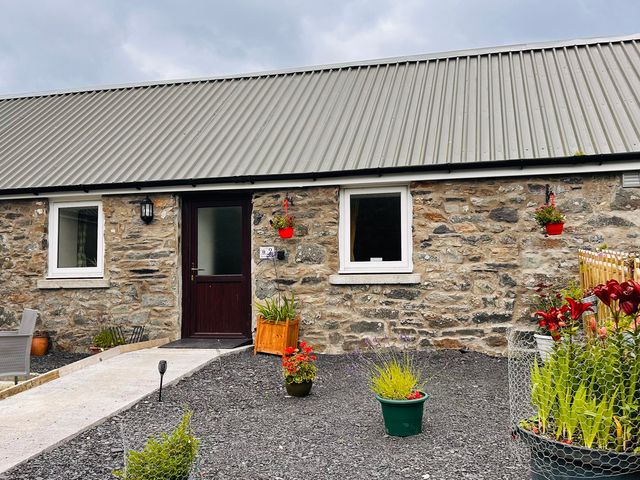 An outdoor area with stone wall and flower pots at Bathach Beag, Balvicar, Isle Of Seil
