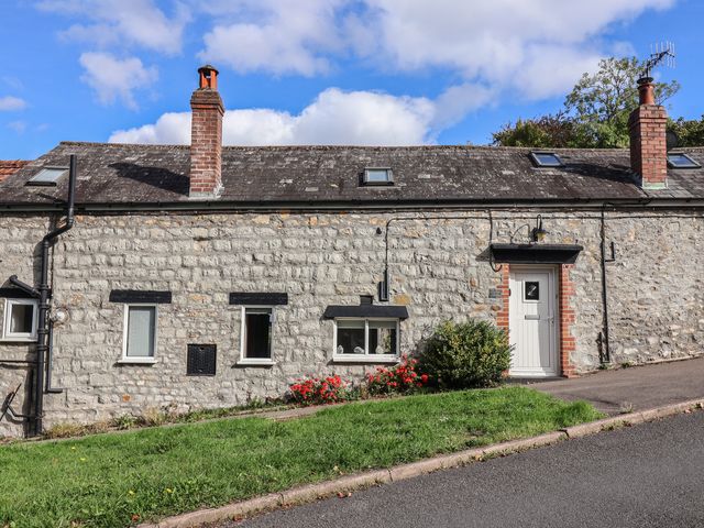 A stone cottage with a garden and pathway at The Well House in Lyme Regis