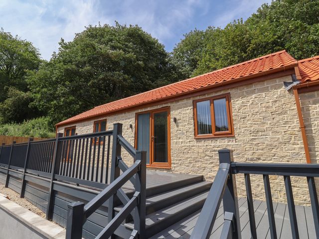 An outdoor area with a stone building and wooden decking at Woodside Scarborough