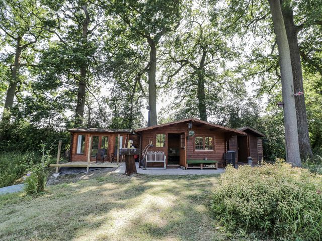 A cabin with a deck and trees in the background at The Lodge