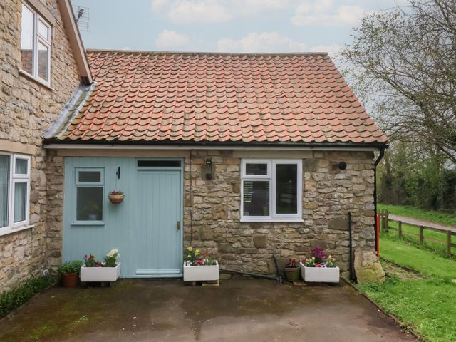 An outdoor view of a stone cottage with a front door and planters at Walnut Cottage in Helmsley