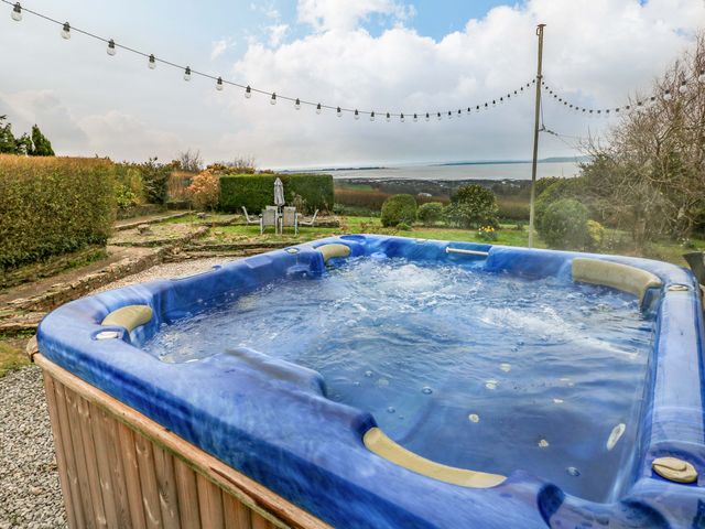 A hot tub in a garden with chairs and pathway at Burry House Llanmorlais