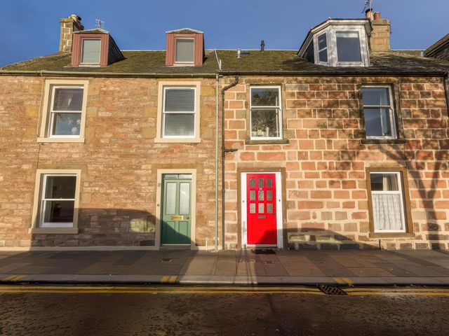 A view of two houses with a green door and red door at River Cottage in Inverness