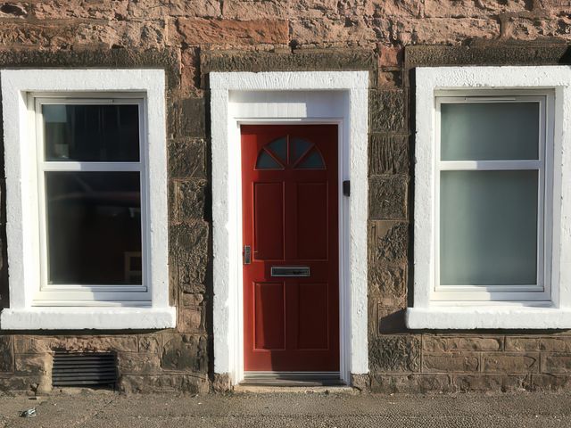 A red door with two windows on either side at 2 Lower Kessock Street in Inverness